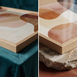 Framed abstract art piece with earthy tones on a textured surface.