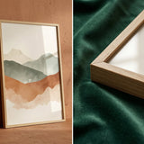 Framed abstract landscape art on a wooden surface with a green fabric background.